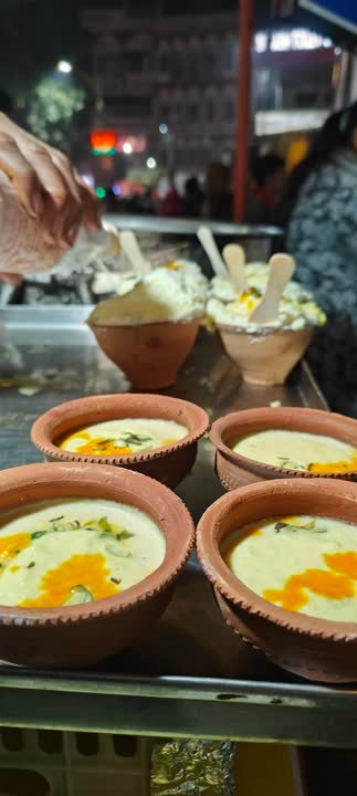 Clay bowls of creamy dessert at a night-time street stall