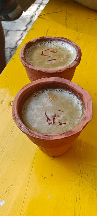 Two clay cups of milk sweet on a yellow counter