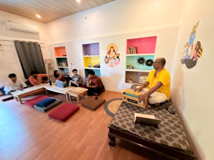 Guests gathered in the common room with a harmonium player