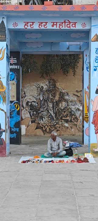 Blue gateway painted with Har Har Mahadev above a seated vendor