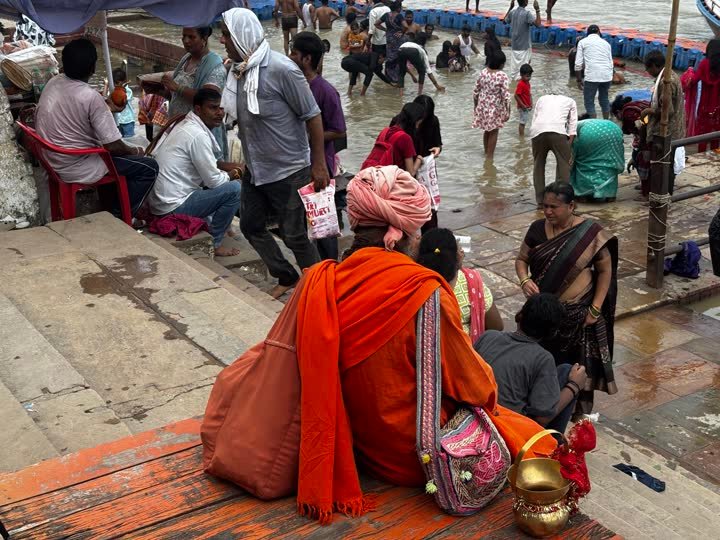 Pilgrims and a sadhu in orange on the wet ghat steps