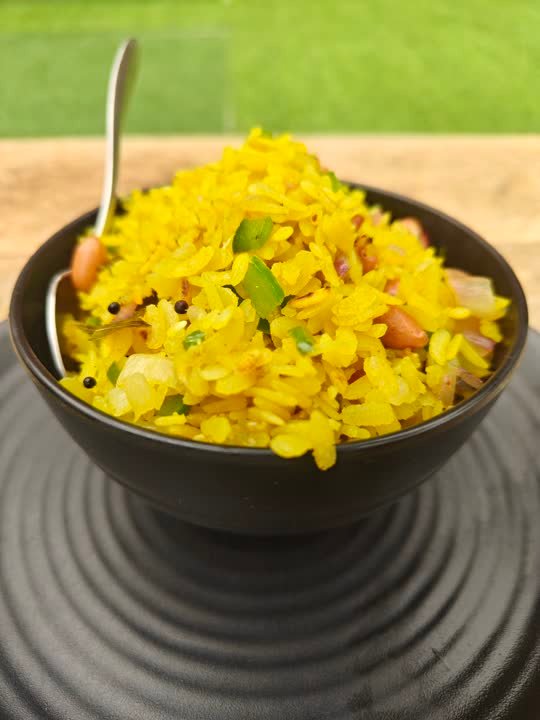 Bowl of yellow poha with peanuts and herbs