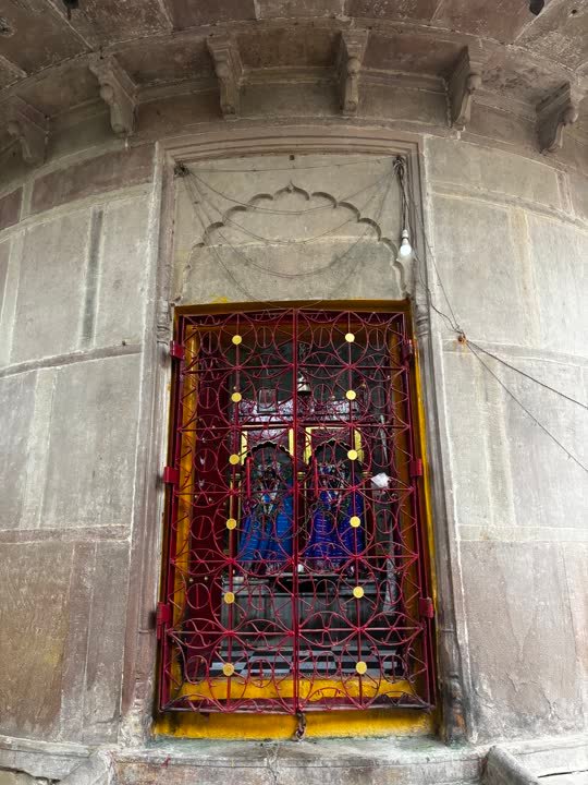 Red lattice shrine window set into a carved stone wall