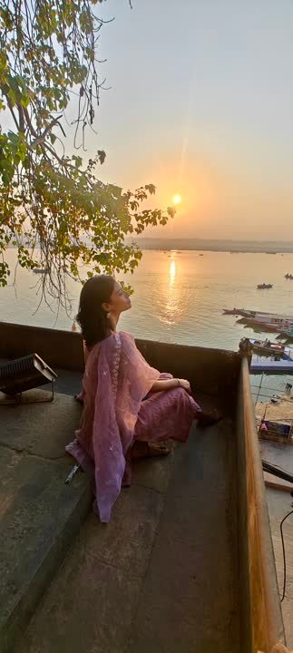 Traveller watching the sun rise over the Ganga from a boat